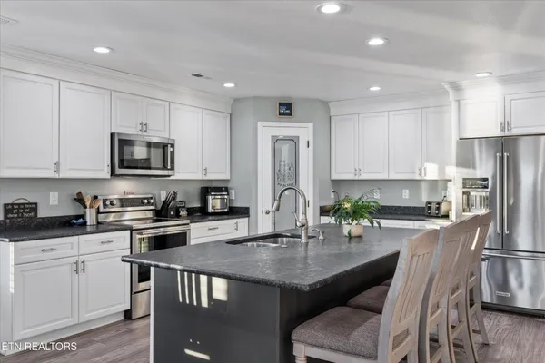 a kitchen with granite countertop a stove a sink a microwave a refrigerator and cabinets