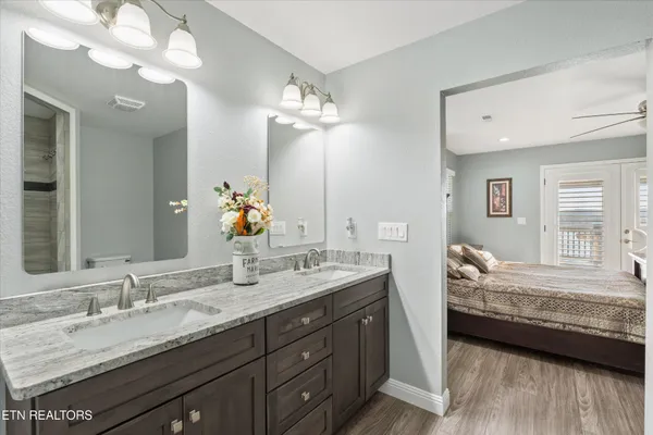 a en suite bathroom with a granite countertop double vanity sink a mirror and a bathtub