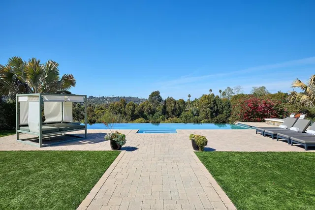 a view of swimming pool with seating area and trees in the background