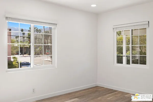 a view of an empty room with wooden floor and windows