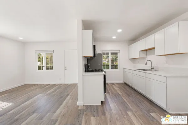 a kitchen with granite countertop a sink cabinets stainless steel appliances and a window