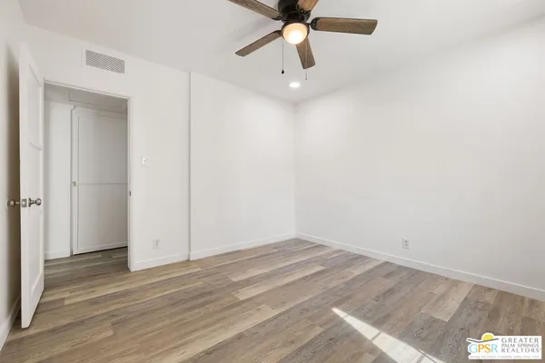 an empty room with a ceiling fan and wooden floor