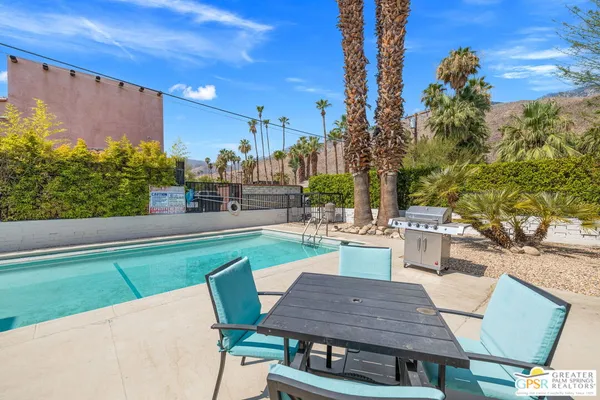 a view of a patio with table and chairs potted plants and palm tree
