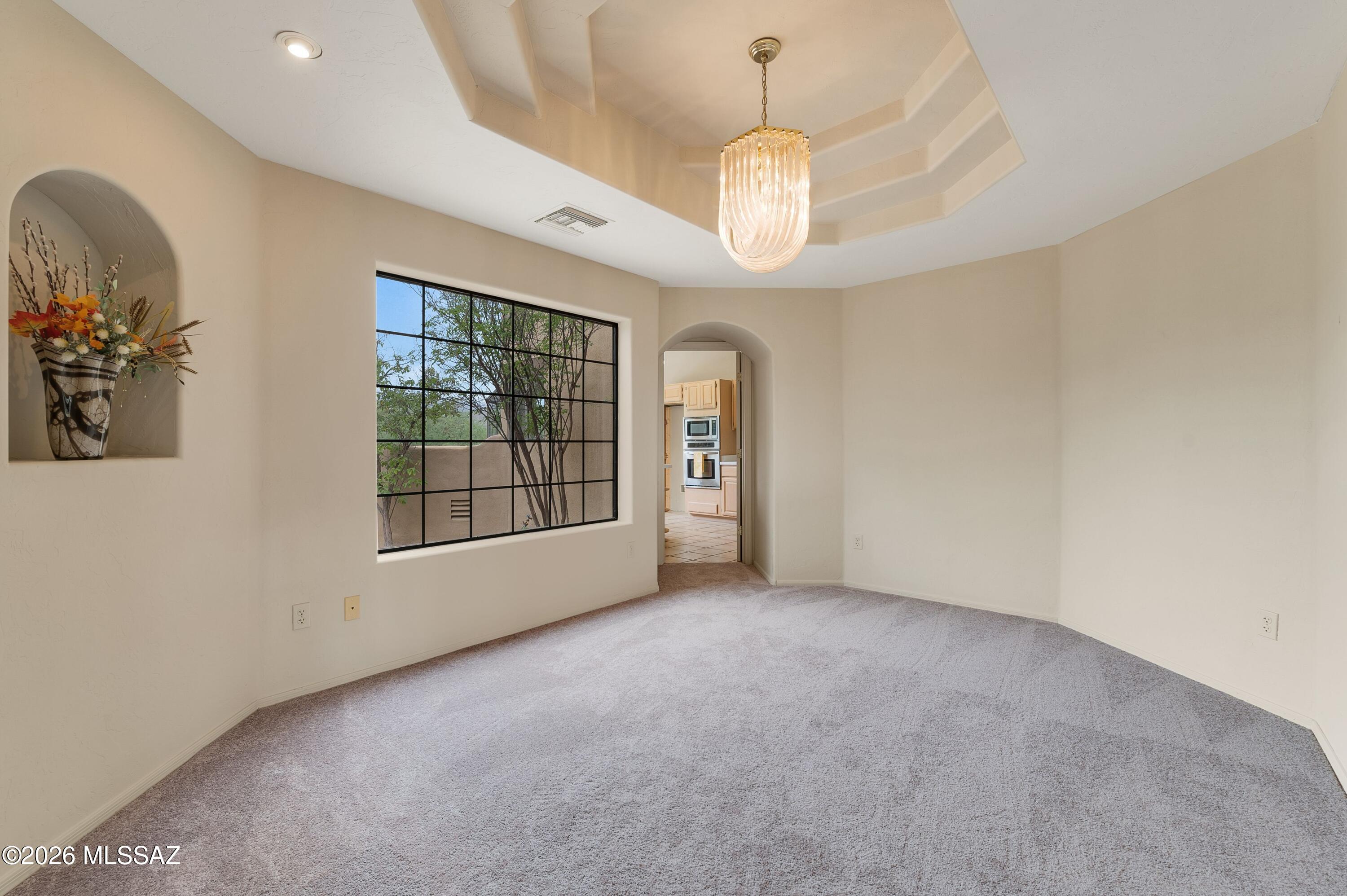 12160 East Tanque Verde Road Tucson, AZ 85749 - Photo 4 of 53 Tray ceiling with a pendant chandelier, picture window, and archway to the kitchen.