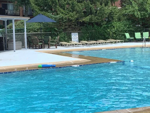 a view of swimming pool with lawn chairs under an umbrella