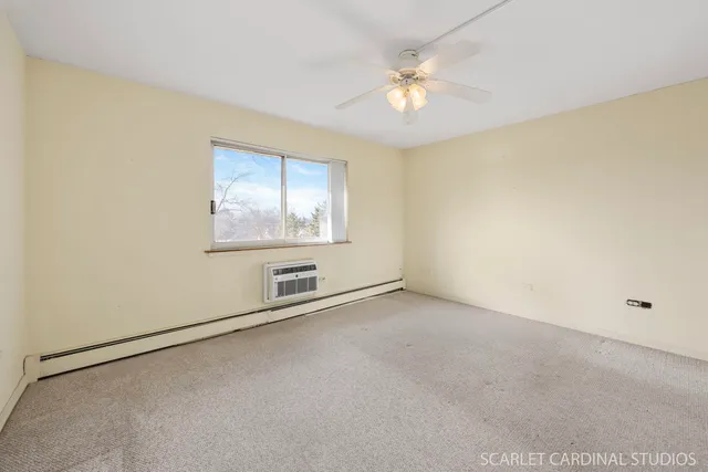 an empty room with a chandelier fan and windows