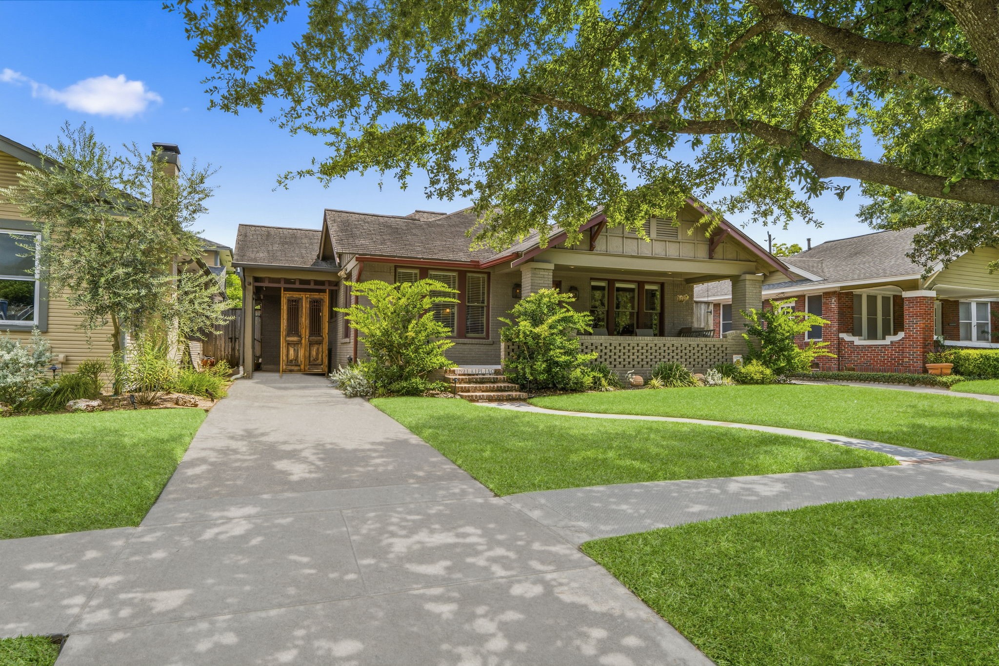 1521 Kipling Street Houston, TX 77006 - Photo 3 of 35 Charming single-story home with a classic front porch, surrounded by lush greenery and mature trees. The pathway leads to a welcoming entrance, perfect for enjoying outdoor relaxation.