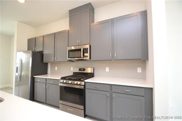 a kitchen with stainless steel appliances granite countertop a refrigerator a sink dishwasher a oven and white cabinets with wooden floor