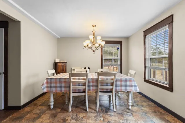 a dining room with wooden floor and chandelier