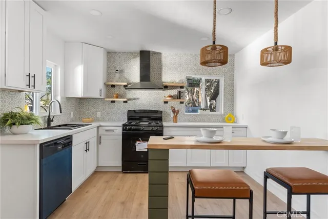 a kitchen with stainless steel appliances granite countertop a stove a sink dishwasher and white cabinets with wooden floor