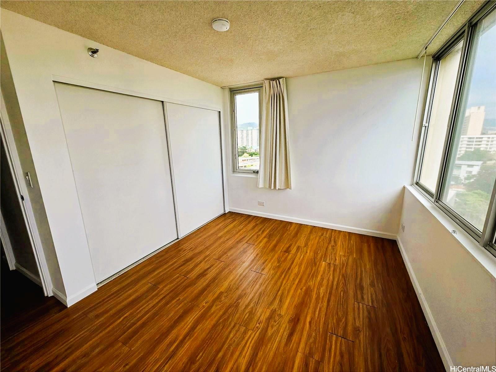 3033 Ala Ilima Street, Unit 1001 Honolulu, HI 96818 - Photo 6 of 12 a view of an empty room with wooden floor and a window
