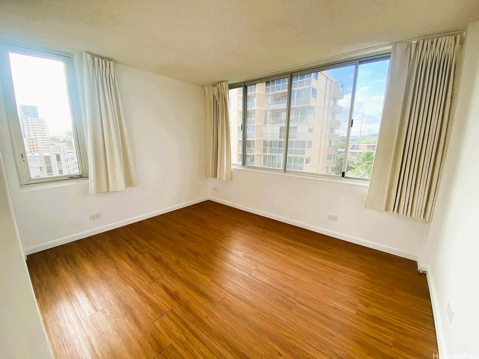3033 Ala Ilima Street, Unit 1001 Honolulu, HI 96818 - Photo 7 of 12 a view of an empty room with wooden floor and a window