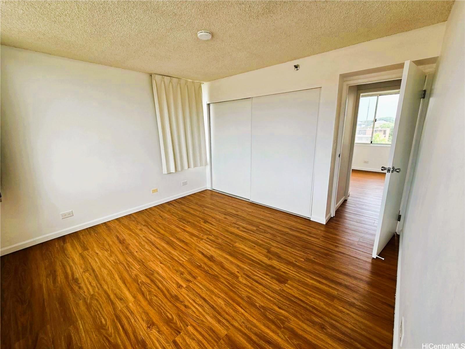 3033 Ala Ilima Street, Unit 1001 Honolulu, HI 96818 - Photo 9 of 12 a view of a room with wooden floor and white walls