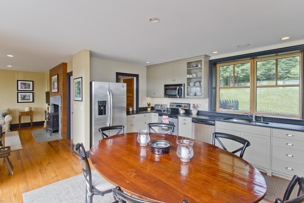 141 Franklin Hill Road Colrain, MA 01340 - Photo 19 of 42 a large dining hall with stainless steel appliances granite countertop a stove a sink a dining table and chairs