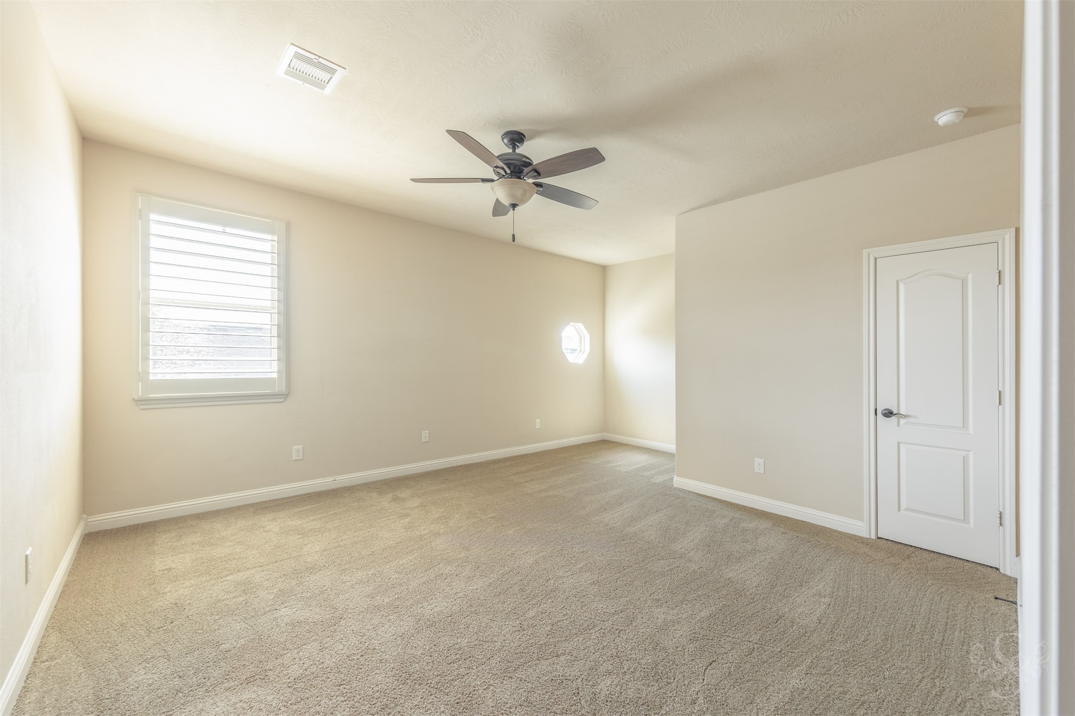 5803 Mustang Ridge Lane Fulshear, TX 77441 - Photo 31 of 48 Spacious secondary bedroom features soft neutral finishes, plush carpeting and windows with plantation shutters that bring in natural light while maintaining privacy. Generous proportions offer flexibility for guests, family or a private home office setup.