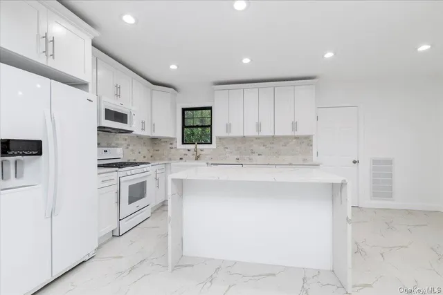 a kitchen with granite countertop white cabinets and white appliances