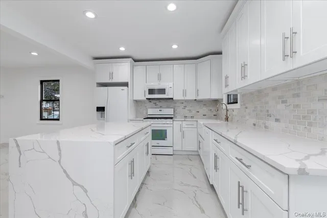 a large white kitchen with stainless steel appliances and white cabinets
