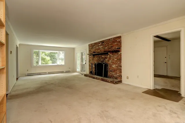 an empty room with windows and fireplace