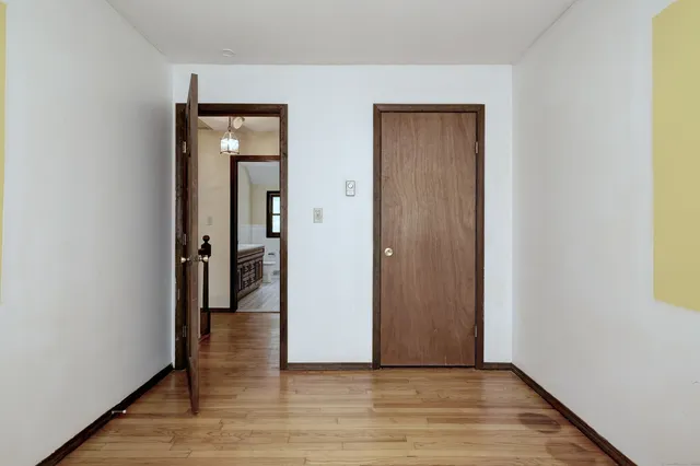 a view of an empty room with wooden floor and a bathroom