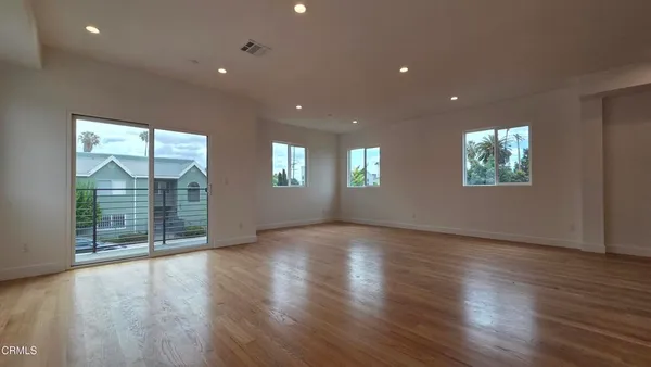 an empty room with wooden floor and windows