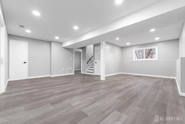 a view of an empty room with wooden floor and window
