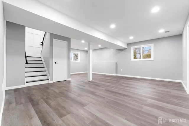 a view of an empty room with wooden floor and windows