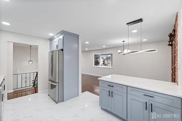 a spacious bathroom with a granite countertop sink a refrigerator and a mirror