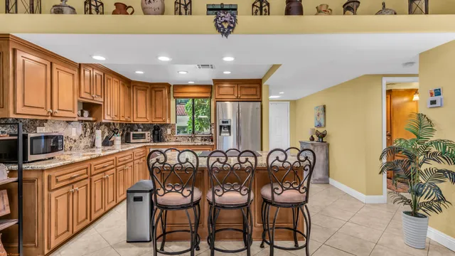 a kitchen with granite countertop lots of white furniture a sink a window and a refrigerator