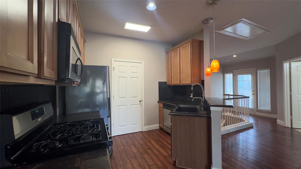 1900 Scofield Ridge Parkway, Unit 5501 Austin, TX 78727 - Photo 3 of 21 A contemporary kitchen space boasts rich hardwood flooring and sleek, dark countertops.
