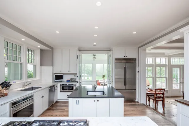 a kitchen with stainless steel appliances kitchen island granite countertop a sink refrigerator and cabinets