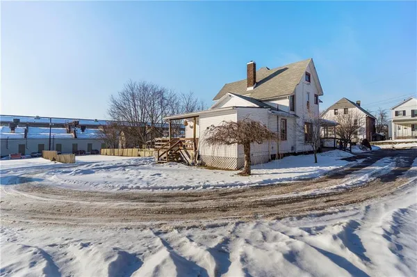 a view of a house with snow on the side of road