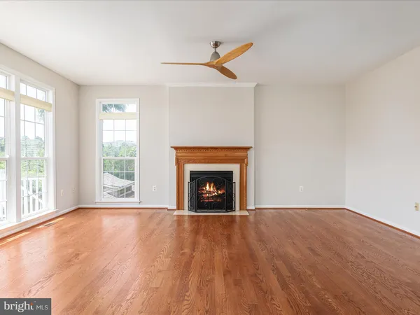 a view of an empty room with wooden floor fireplace and a window