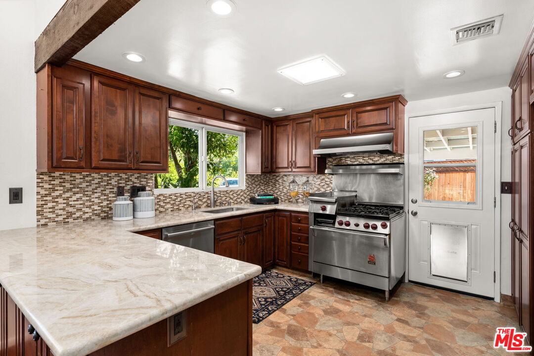 11080 Plainview Avenue Tujunga, CA 91042 - Photo 11 of 41 a kitchen with stainless steel appliances granite countertop wooden cabinets a stove a sink and a microwave