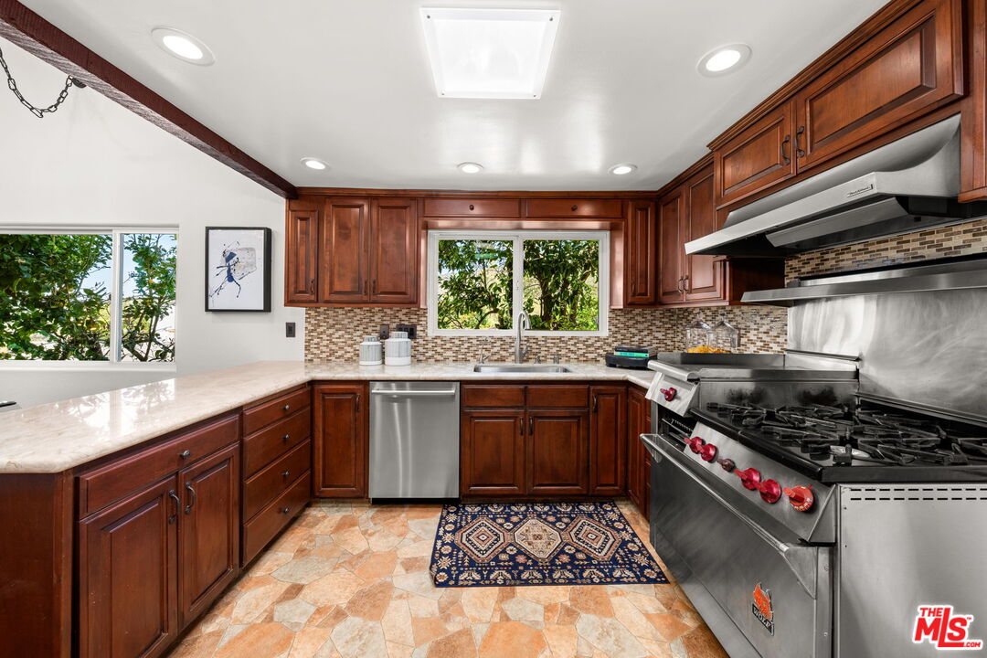 11080 Plainview Avenue Tujunga, CA 91042 - Photo 13 of 41 a kitchen with stainless steel appliances granite countertop a stove a sink dishwasher and cabinets with wooden floor