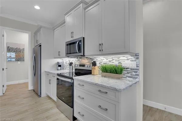 a kitchen with white cabinets and appliances
