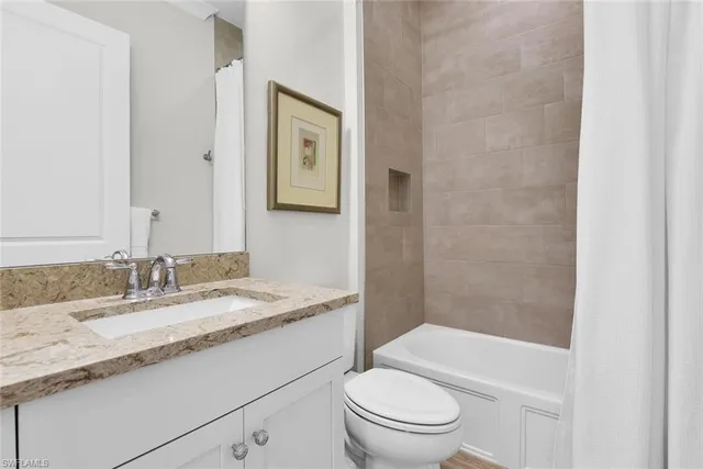 a bathroom with a granite countertop sink a toilet and shower