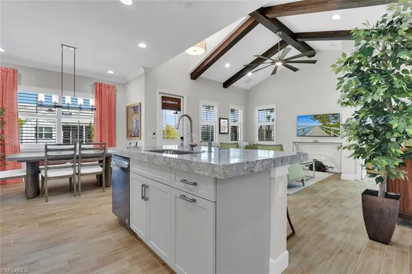 a kitchen with stainless steel appliances granite countertop a sink dishwasher a stove a dining table and chairs with wooden floor