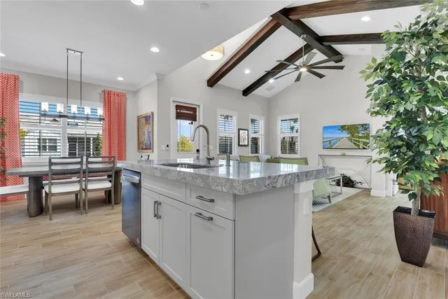 a kitchen with stainless steel appliances granite countertop a sink dishwasher a stove a dining table and chairs with wooden floor