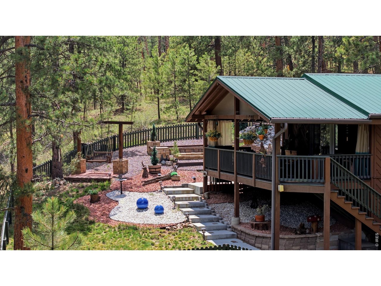 102 Insmont Drive Bailey, CO 80421 - Photo 3 of 43 Custom fenced in yard with 2 decks, gorgeous landscaping, fire pit, and stunning water feature