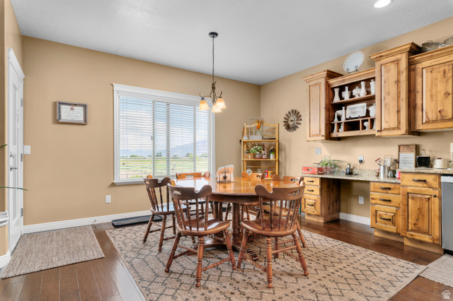 5702 950 North Ogden, UT 84404 - Photo 15 of 36 Dining area featuring wood-finish flooring, a large window with horizontal blinds, built-in wooden cabinetry with open shelving, and a granite-look countertop