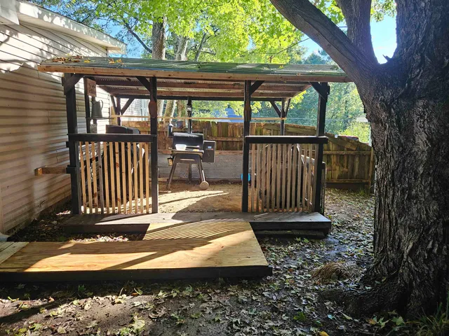 a view of a patio with a table chairs and a barbeque