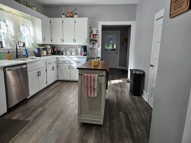 a kitchen with cabinets appliances wooden floor and a window