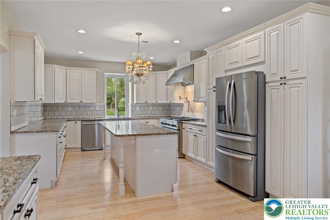 1790 Friedensville Road Bethlehem, PA 18015 - Photo 16 of 50 a kitchen with kitchen island granite countertop a refrigerator a sink dishwasher a stove and white cabinets with wooden floor