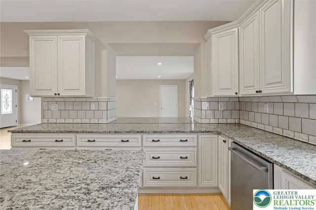 a kitchen with granite countertop white cabinets and stainless steel appliances