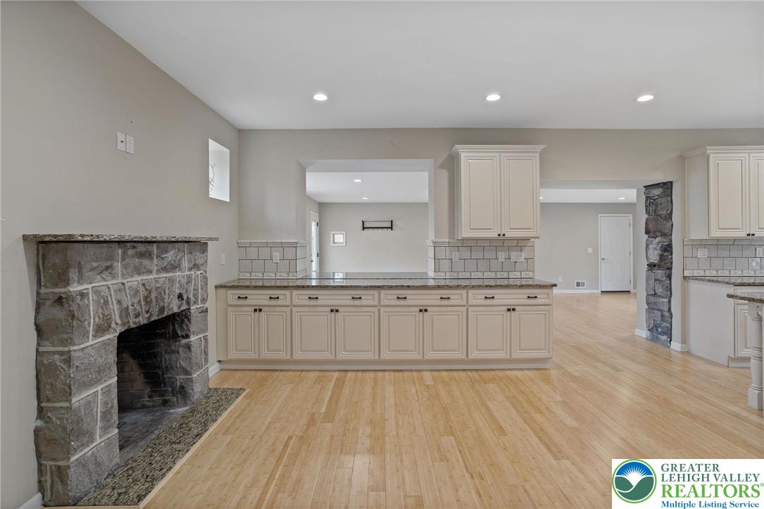1790 Friedensville Road Bethlehem, PA 18015 - Photo 23 of 50 a large kitchen with granite countertop a stove top oven a sink dishwasher and a fireplace with wooden floor