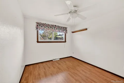 an empty room with wooden floor chandelier fan and windows