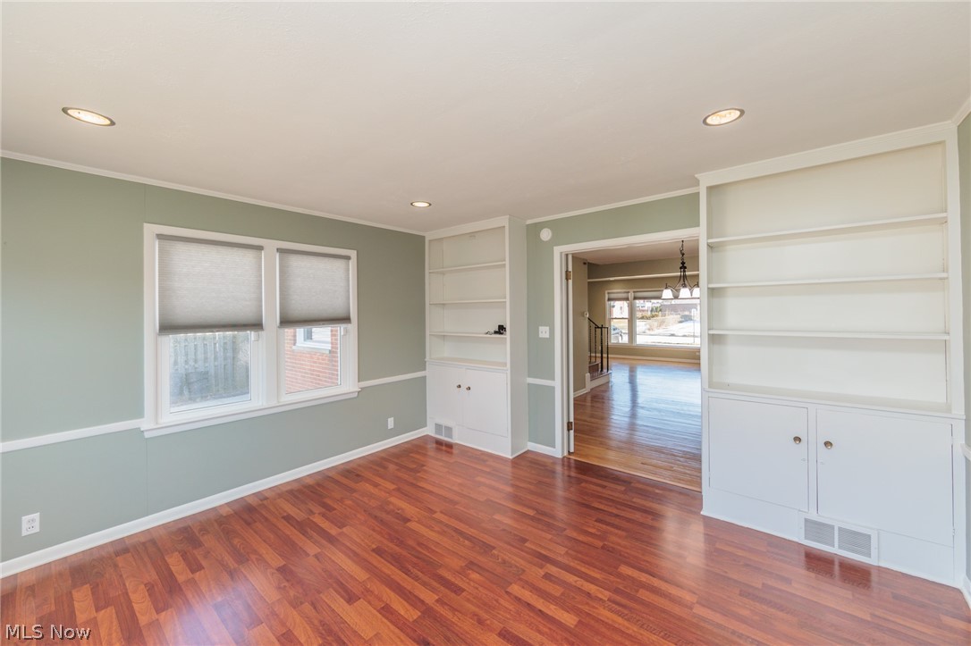 2444 Dysart Road Cleveland, OH 44118 - Photo 9 of 44 Empty room featuring ornamental molding, hardwood / wood-style floors, a notable chandelier, and built in features
