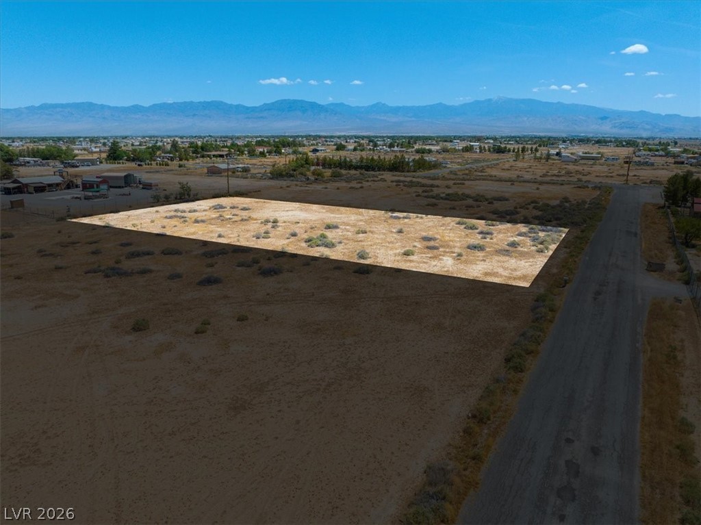 4580 Lawrence Road Pahrump, NV 89048 - Photo 1 of 40 A vast, level lot awaits your vision, framed by distant mountains under an expansive sky.