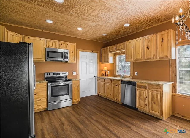 a kitchen with stainless steel appliances granite countertop a refrigerator a stove top oven a sink and dishwasher