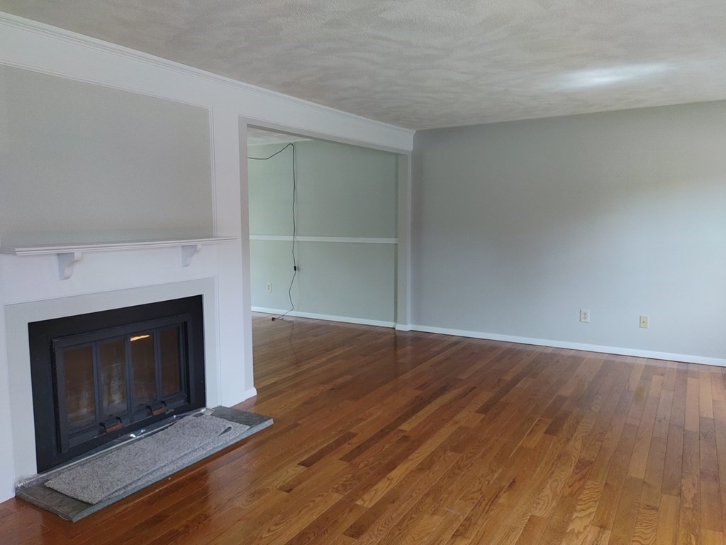 116 Russet Lane, Unit 116 Boxborough, MA 01719 - Photo 2 of 22 a view of an empty room with wooden floor fireplace and a window